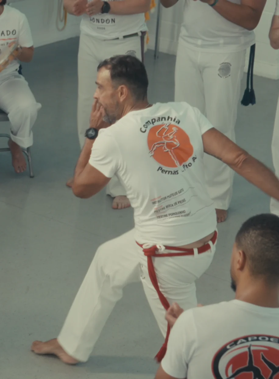 A capoeirista with a red cord moving through the roda